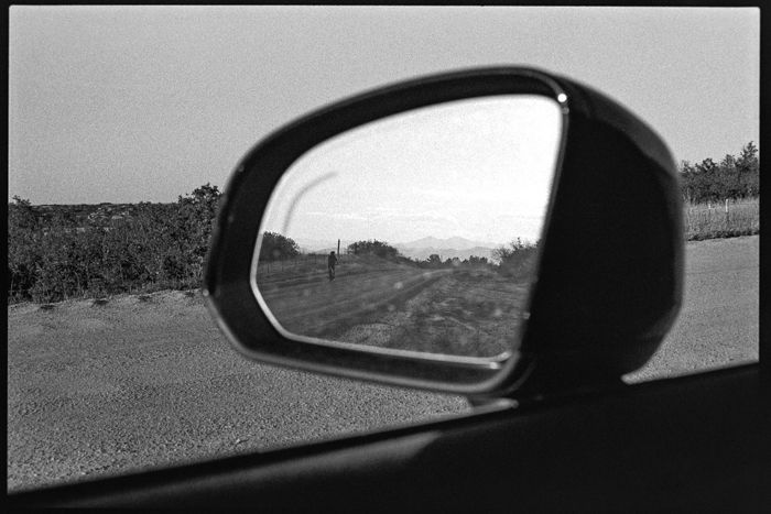 an image of a cyclist on a dirt road in the rearview mirror